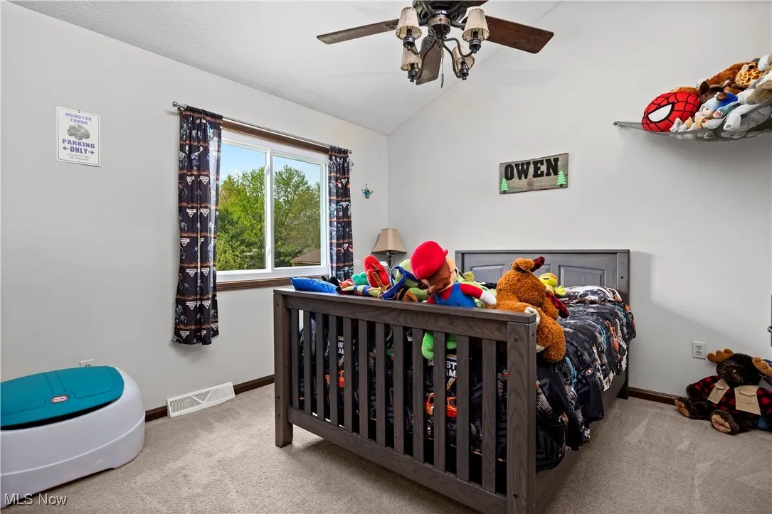 Carpeted bedroom featuring lofted ceiling and ceiling fan