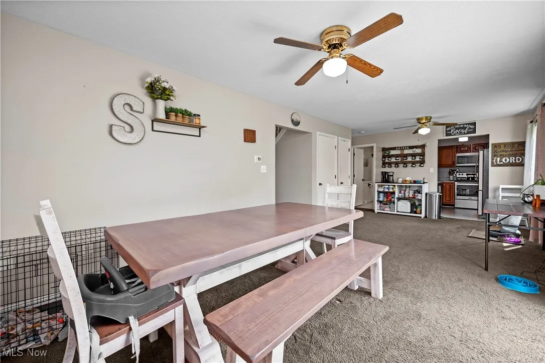 Dining area with light carpet and a ceiling fan