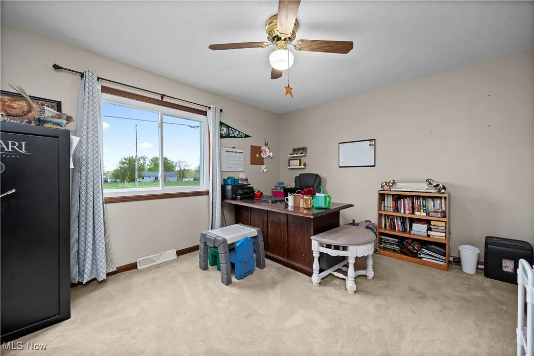 Office area featuring light carpet and a ceiling fan