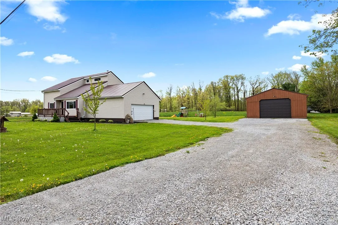 View of home's exterior featuring a yard, a metal roof, a deck, and an outbuilding