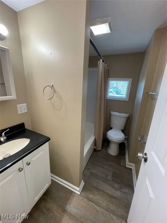 Bathroom featuring dark wood-type flooring, vanity, and shower / bath combo with shower curtain