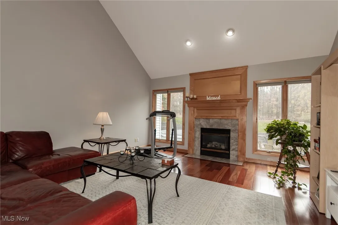 Living room with dark wood-style flooring, a fireplace, lofted ceiling, and recessed lighting