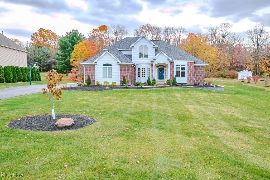Traditional home with a front yard, brick siding, and roof with shingles