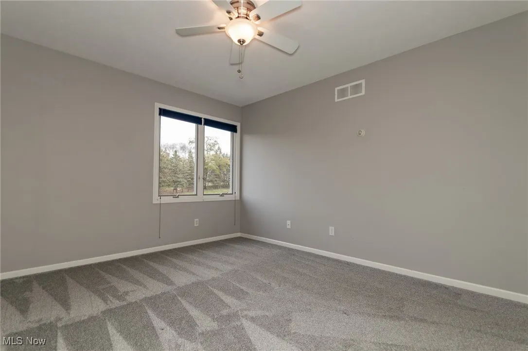 Carpeted empty room with baseboards and ceiling fan