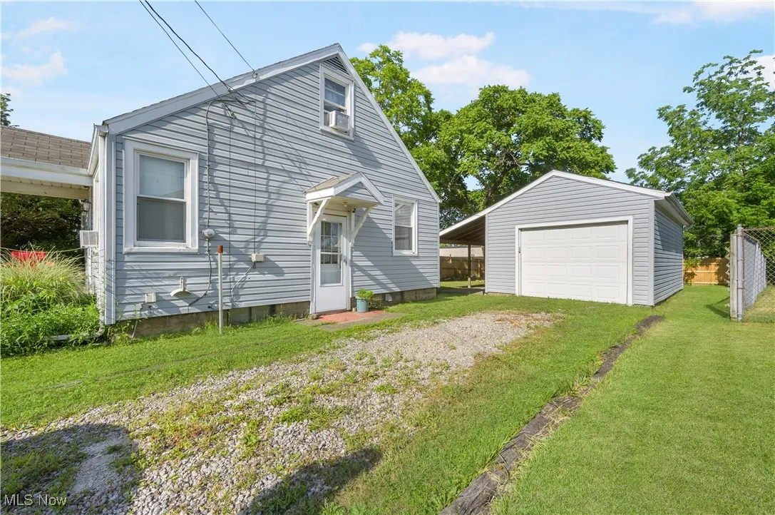View of front of house with a garage, an outdoor structure, and driveway