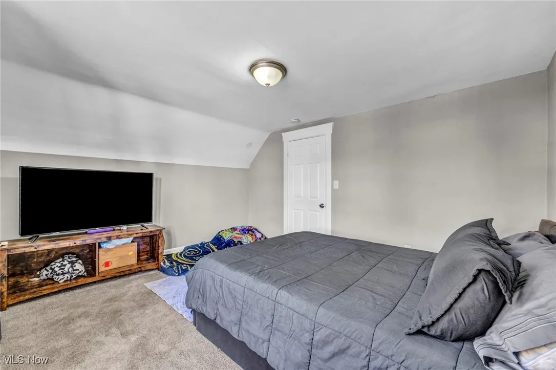 Bedroom with carpet floors and vaulted ceiling