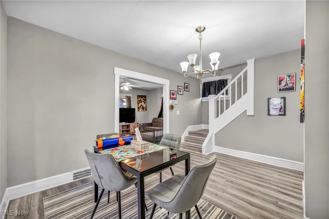 Dining space with stairs, a chandelier, wood finished floors, and a ceiling fan