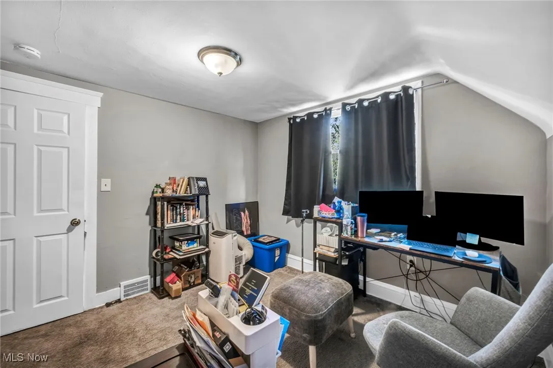 Home office with carpet floors and lofted ceiling