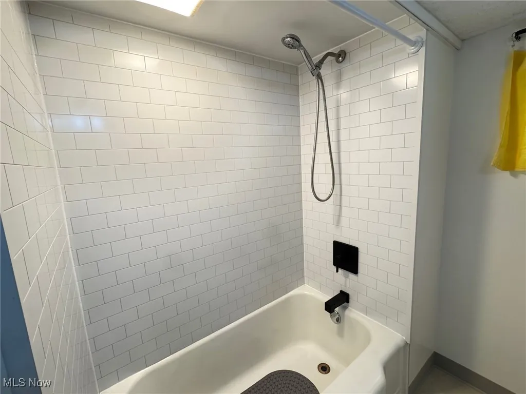 basement Full bath with shower / washtub combination and baseboards