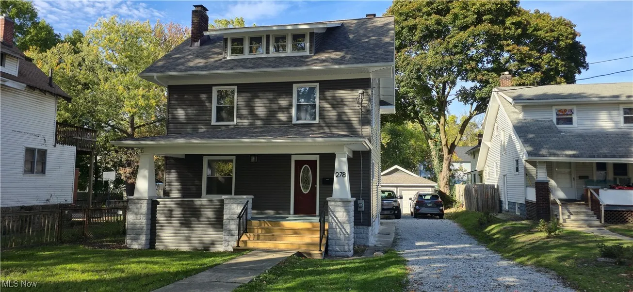 American foursquare style home with a porch, roof with shingles, and an outbuilding
