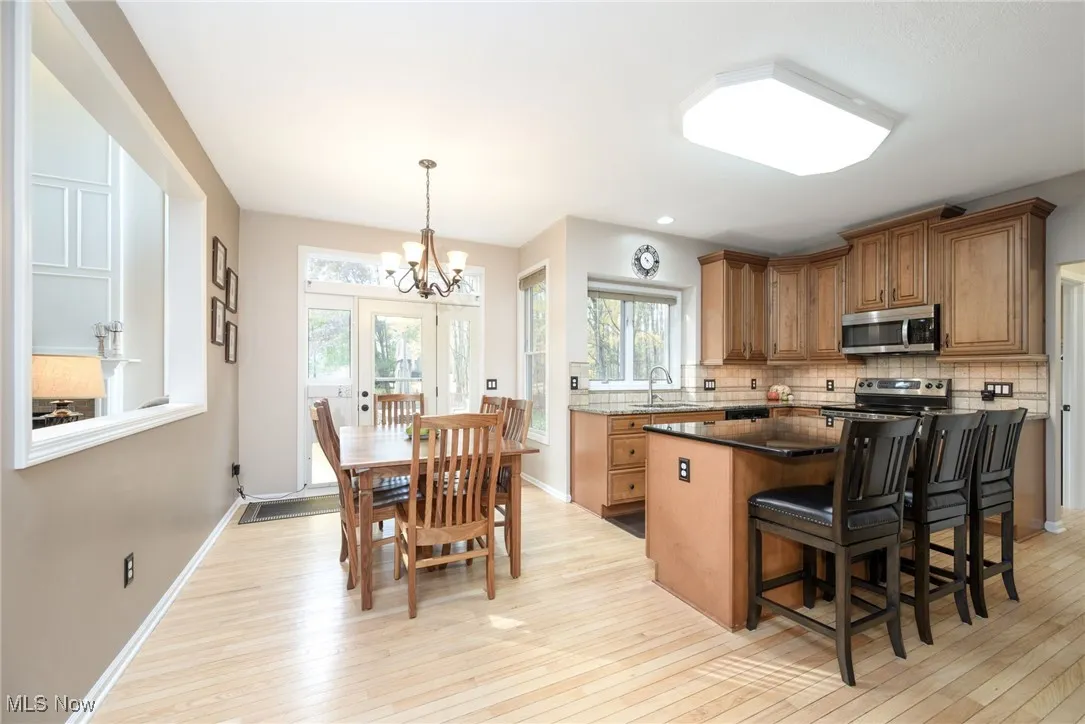 Kitchen featuring backsplash, a kitchen bar, dark stone counters, brown cabinetry, and recessed lighting