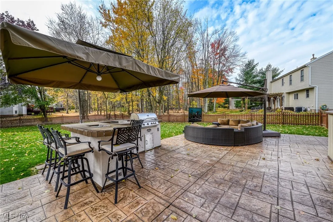 Fenced backyard with an outdoor hangout area, a patio, and an outdoor kitchen