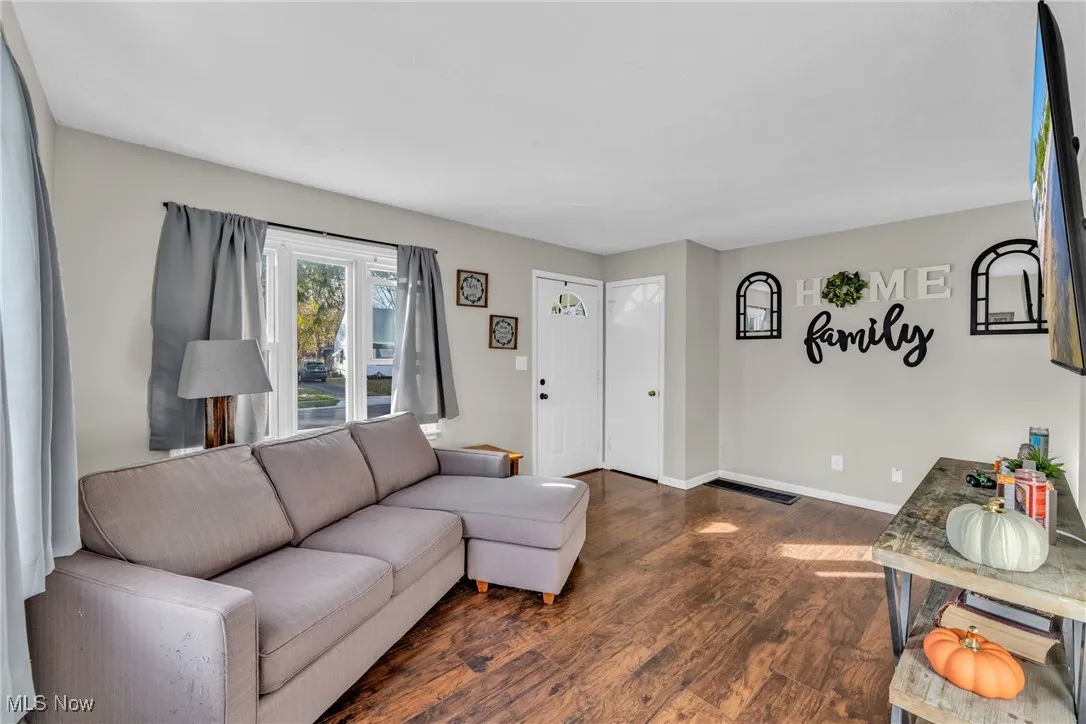 Living area featuring dark wood-type flooring and baseboards