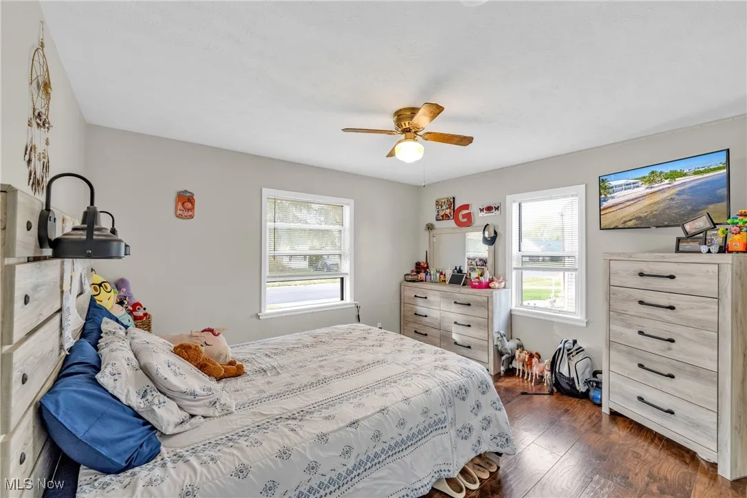 Bedroom featuring dark wood-style floors, multiple windows, and ceiling fan