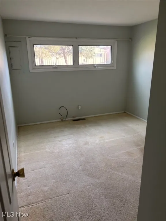 Empty room with light colored carpet and baseboards