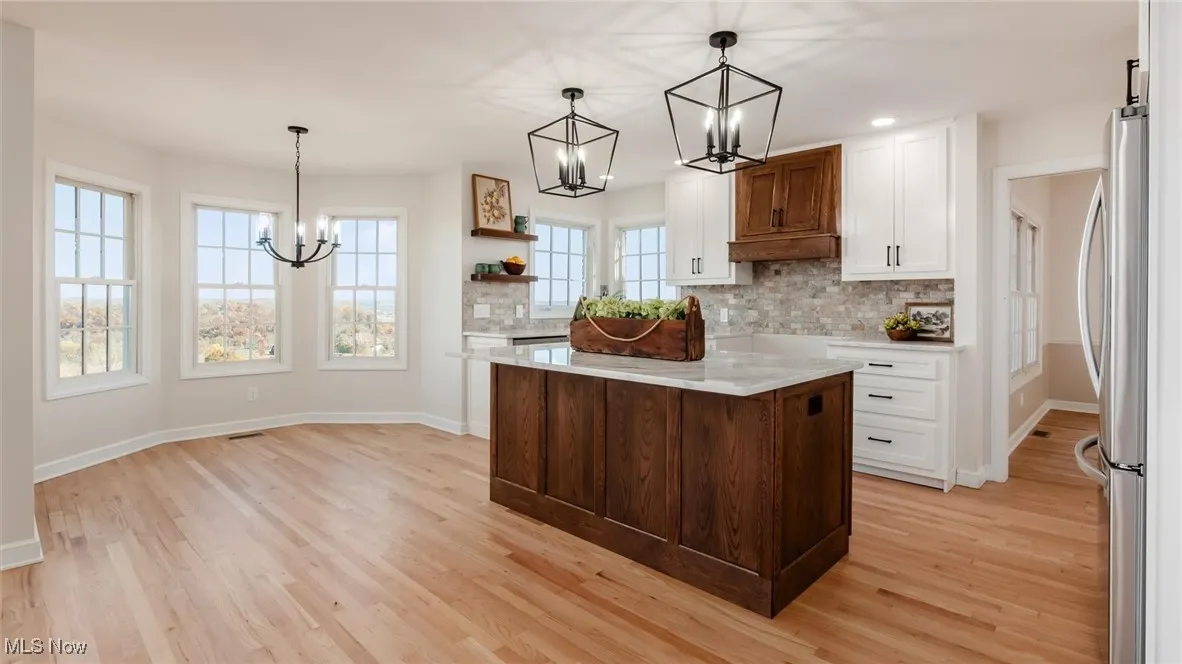 Kitchen with pendant lighting, a chandelier, backsplash, white cabinets, and recessed lighting