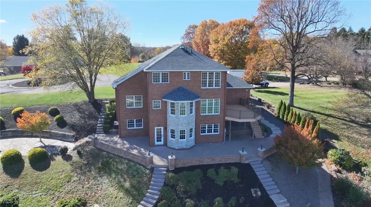 Back of property featuring stairway, a lawn, and brick siding
