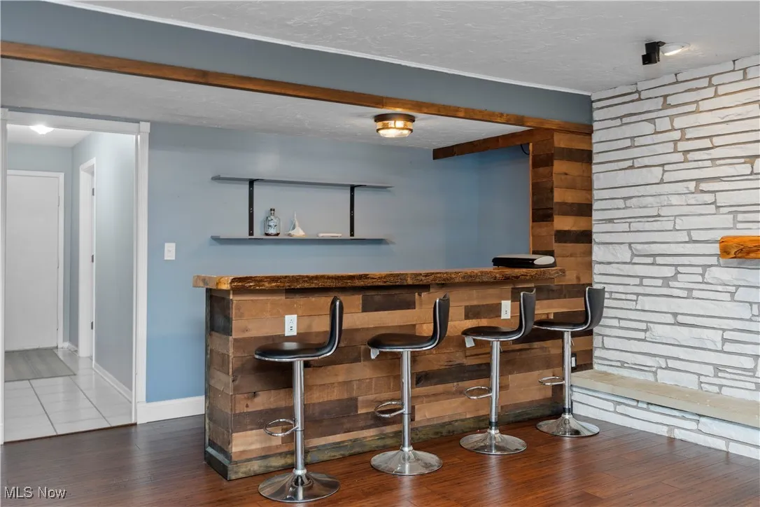 Indoor dry bar featuring a textured ceiling, dark wood-type flooring, and open shelves