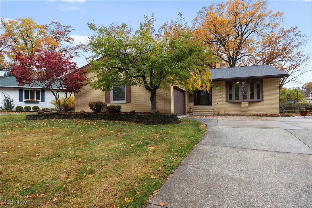 Ranch-style home featuring driveway, a front lawn, brick siding, a porch, and a garage