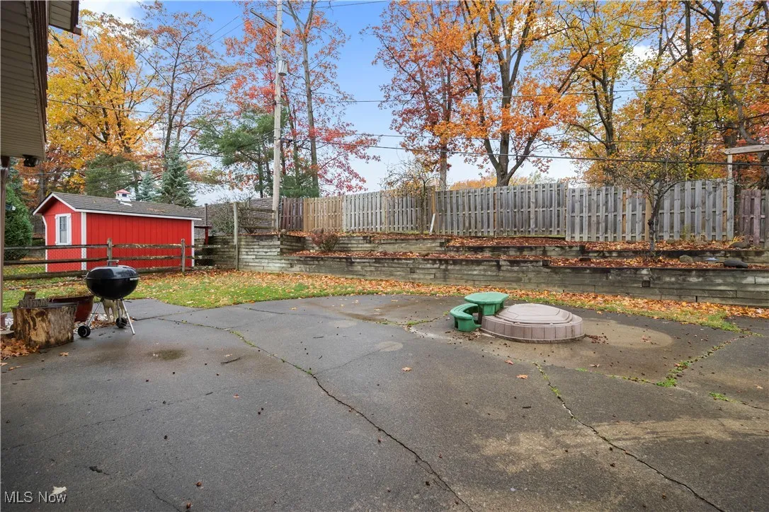 Fenced backyard with area for grilling, a patio, and an outdoor structure