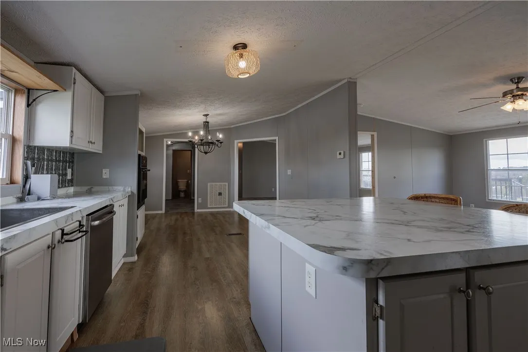 Kitchen with plenty of natural light, ornamental molding, light countertops, dark wood finished floors, and a textured ceiling