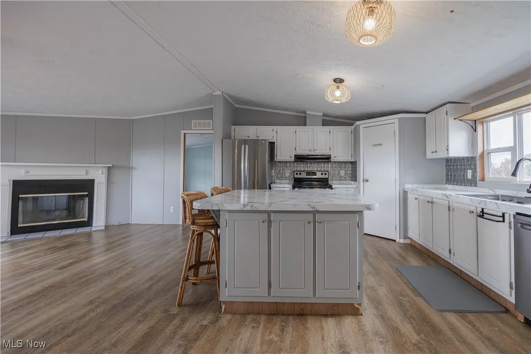 Kitchen with a kitchen island, a kitchen breakfast bar, tasteful backsplash, open floor plan, and light wood-type flooring