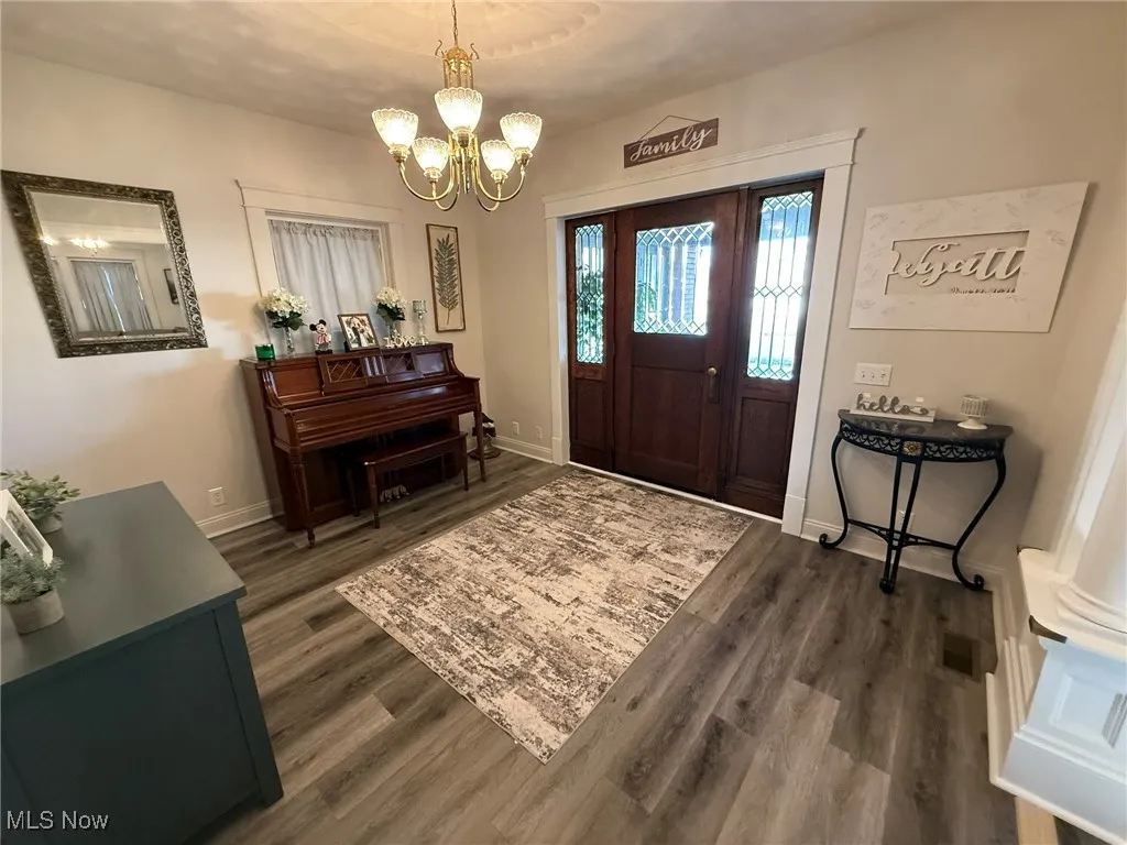Foyer with dark wood-type flooring and a chandelier