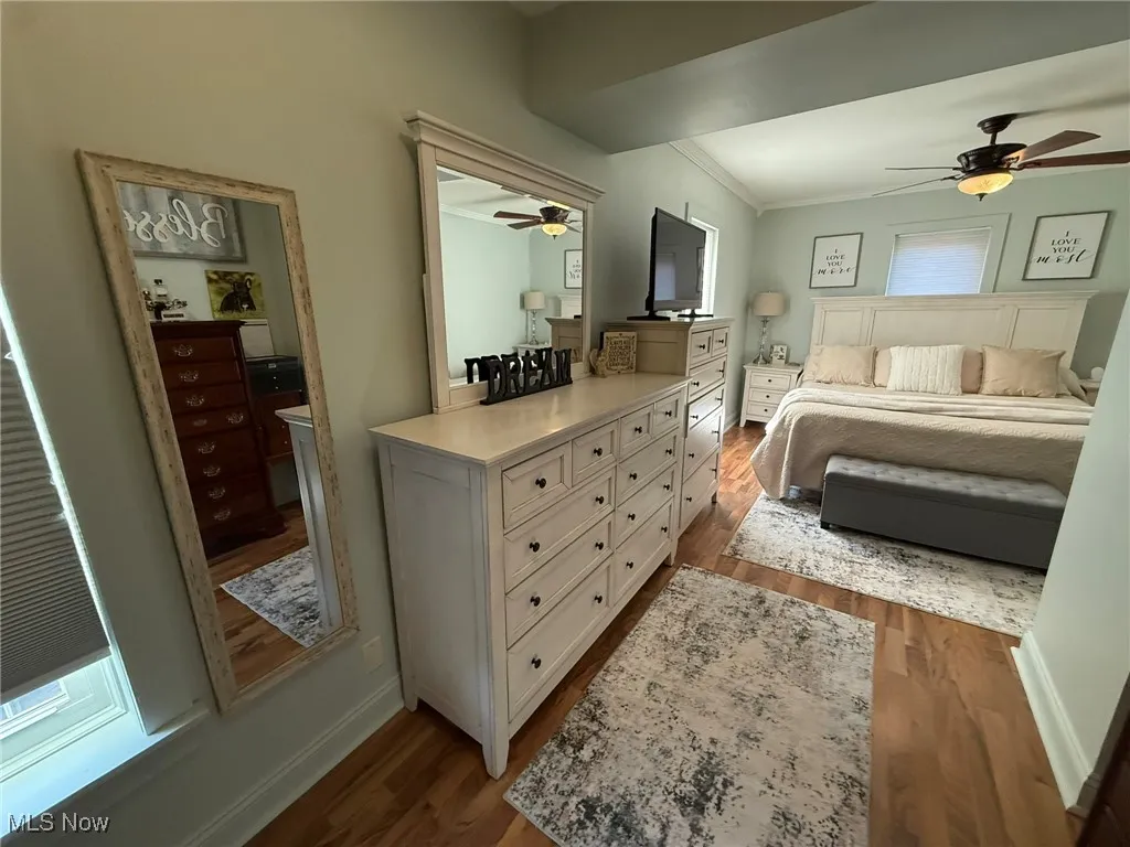 Bedroom with dark wood-style flooring and crown molding