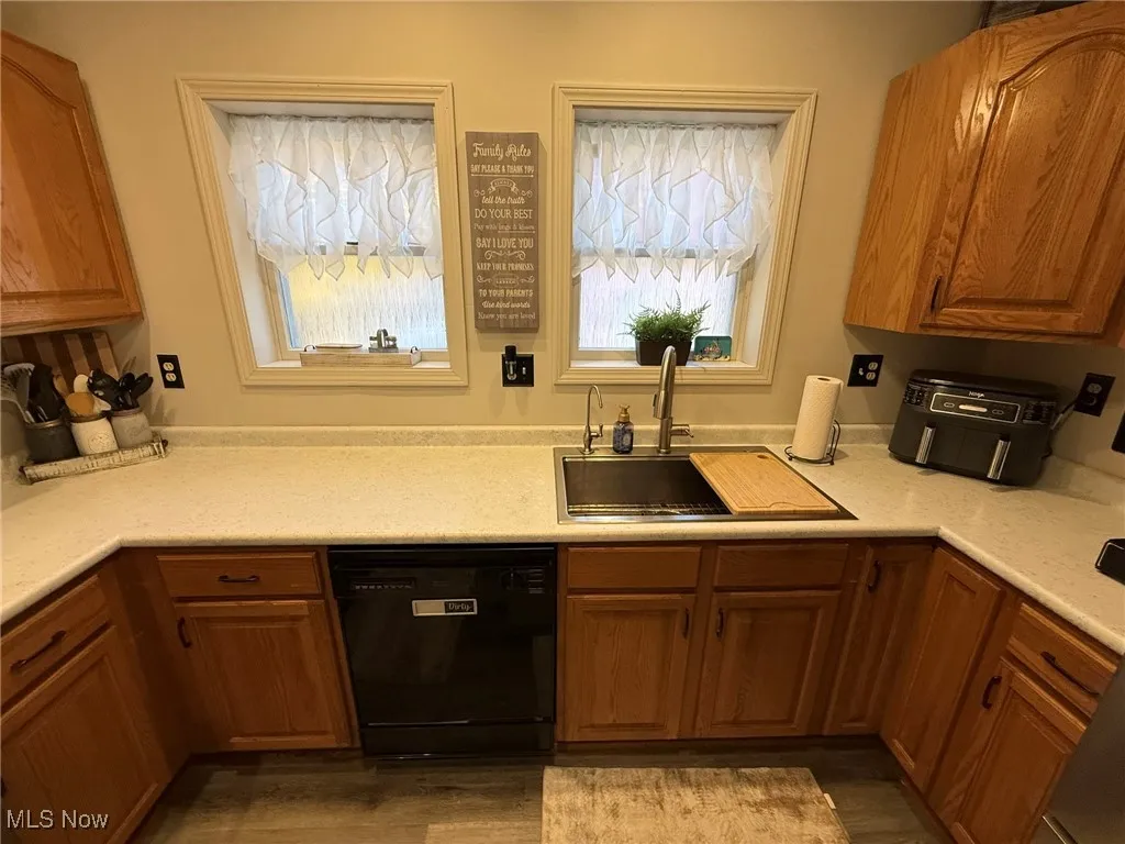Kitchen featuring black dishwasher, brown cabinets, and dark wood-style flooring