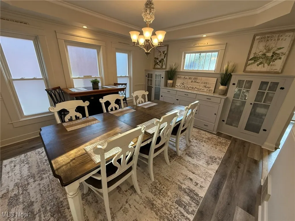 Dining space with crown molding, light wood-style flooring, a chandelier, and a tray ceiling
