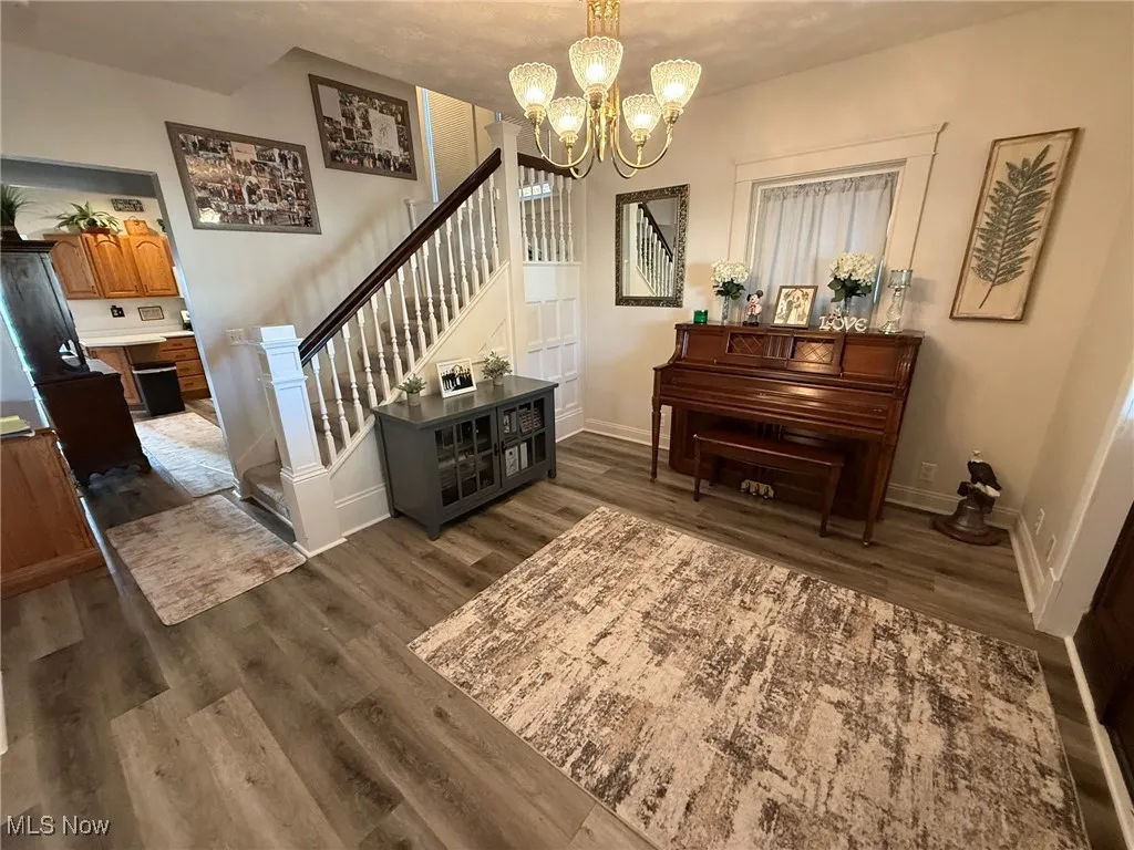 Living area featuring dark wood-type flooring, a chandelier, and stairway
