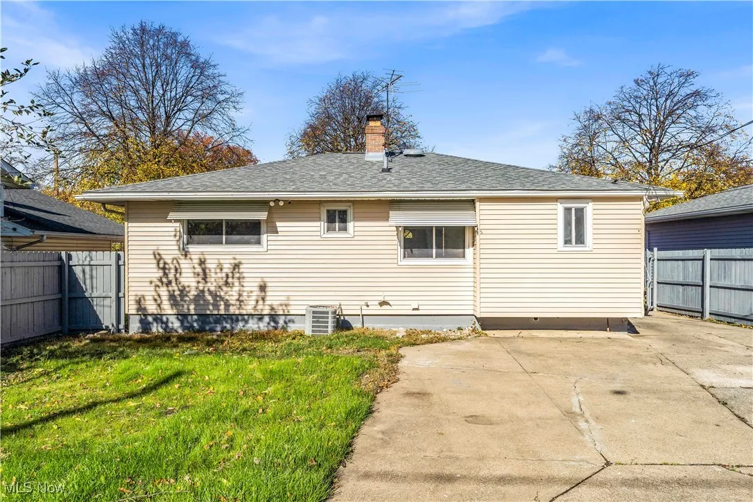 Back of house with a chimney and roof with shingles