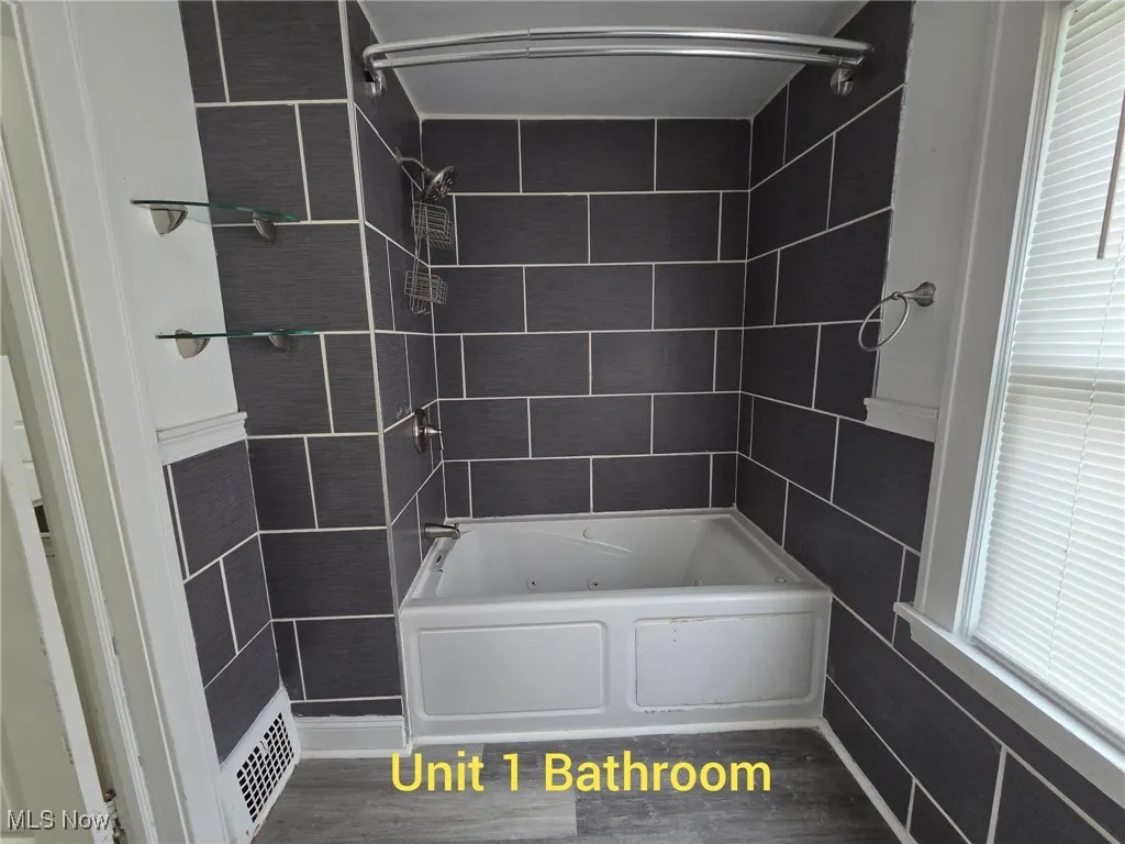 Full bathroom with a combined bath / shower with jetted tub and dark wood finished floors