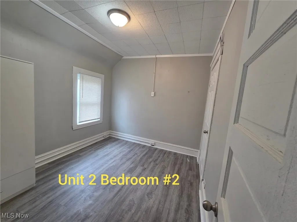 Unfurnished room with dark wood-style floors and ornamental molding