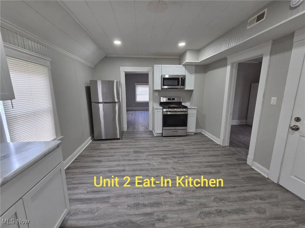 Kitchen featuring light countertops, white cabinets, dark wood finished floors, appliances with stainless steel finishes, and recessed lighting