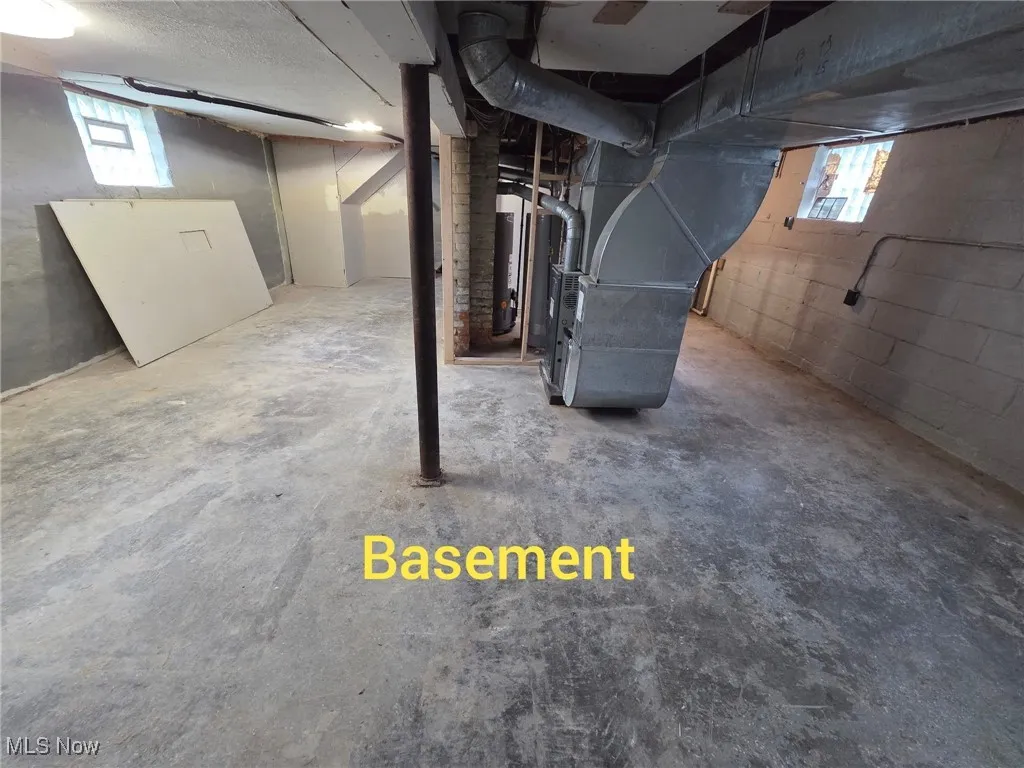 Below grade area with plenty of natural light, heating unit, and water heater