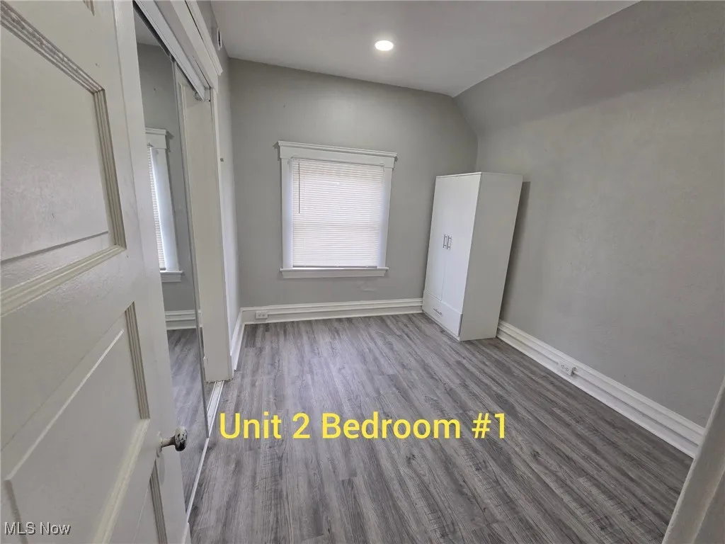 Unfurnished room with wood finished floors and lofted ceiling