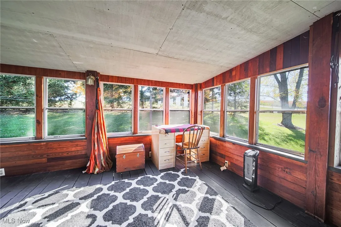 Sunroom featuring wooden walls, hardwood / wood-style flooring, and a water view