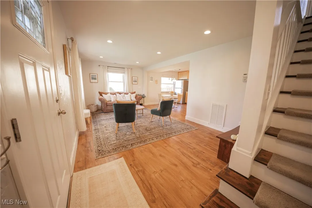 Living room featuring stairs, recessed lighting, and light wood-style floors