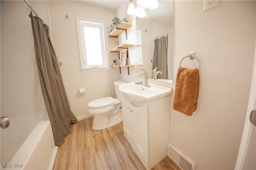 Bathroom featuring vanity, shower / tub combo with curtain, and light wood-style floors