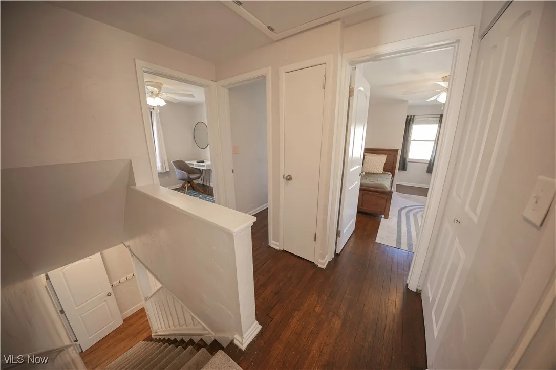 Hall featuring an upstairs landing and dark wood-type flooring