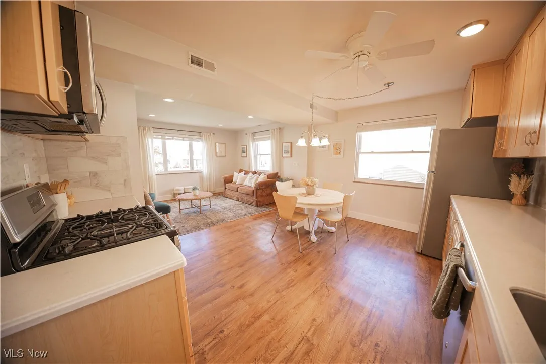 Kitchen with recessed lighting, light wood-style floors, stainless steel appliances, decorative backsplash, and open floor plan