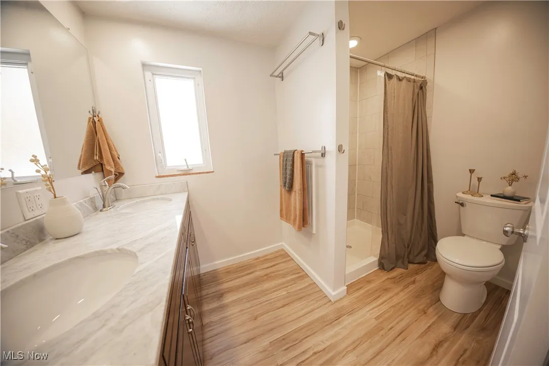 Bathroom with double vanity, a shower stall, and light wood finished floors