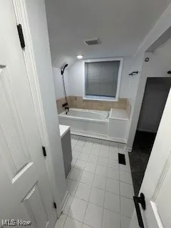Full bathroom featuring a bath, vanity, and light tile patterned flooring