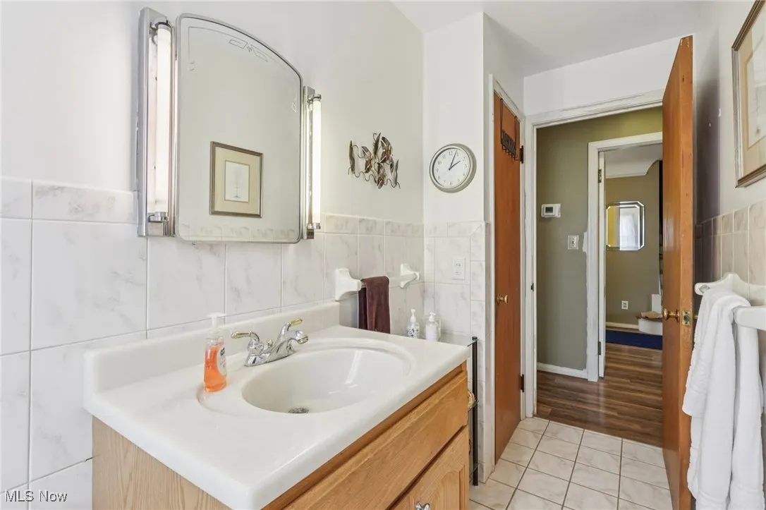 Bathroom featuring vanity, light tile patterned floors, and tile walls