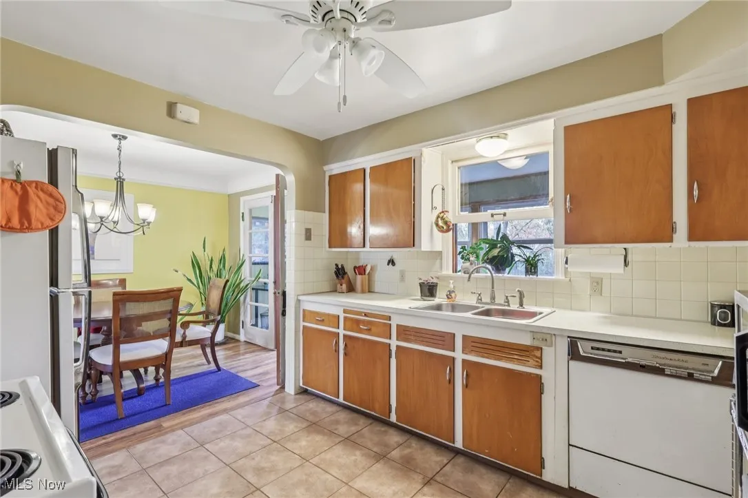 Kitchen featuring white appliances, light countertops, pendant lighting, backsplash, and brown cabinets