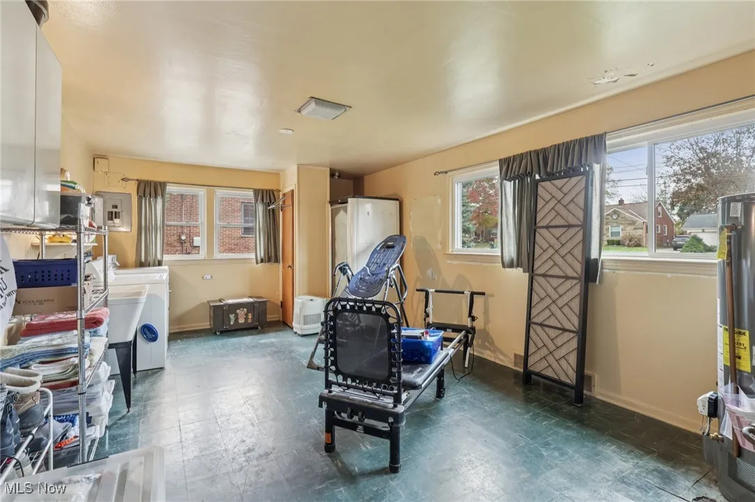 Recreation room with dark floors, healthy amount of natural light, electric panel, and gas water heater