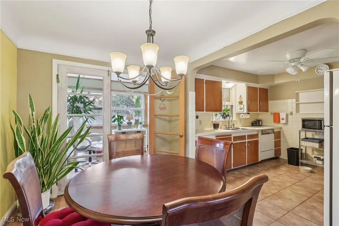 Dining room with a ceiling fan, light tile patterned flooring, and a chandelier