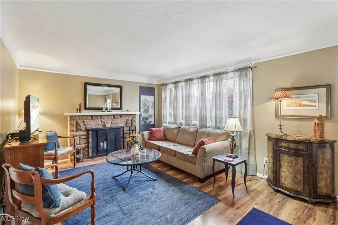 Living room with a fireplace, wood finished floors, and crown molding