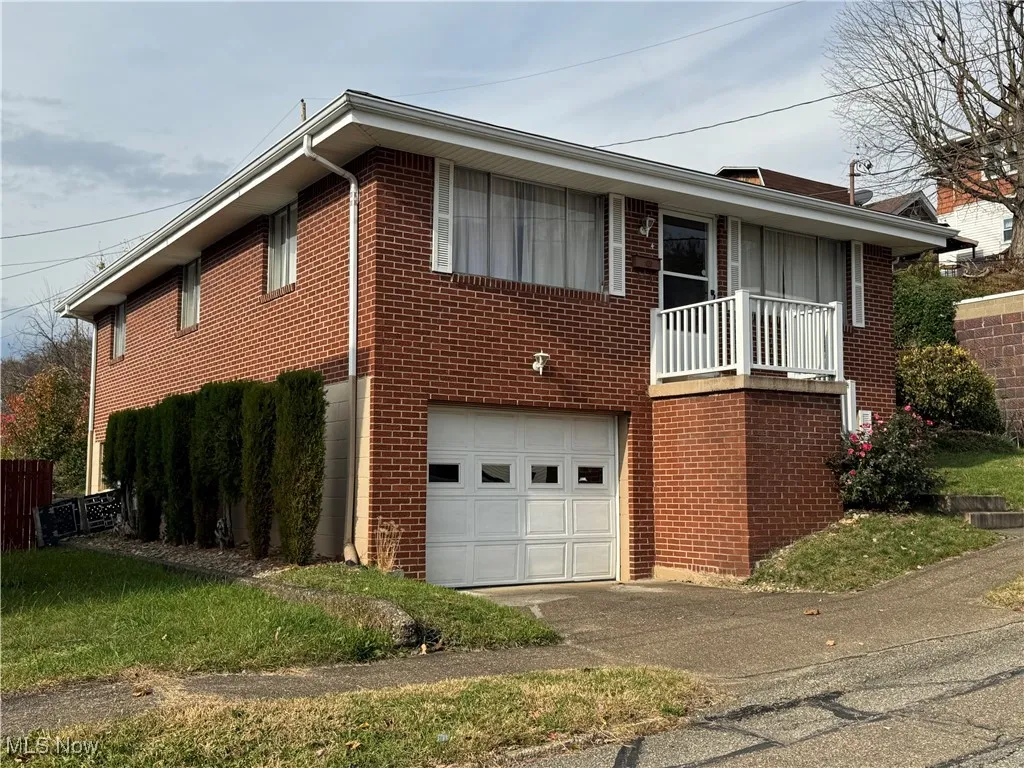 View of front of home with a balcony, brick siding, an attached garage, and driveway